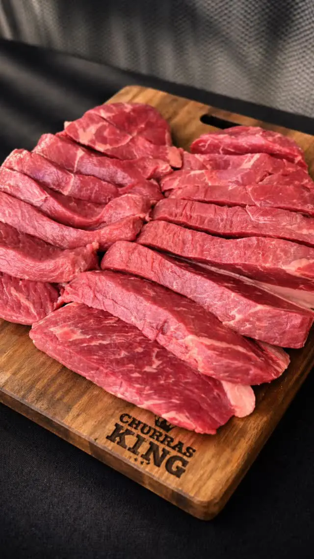 Cortes de carne crua numa tábua de madeira com o logótipo ChurrasKing