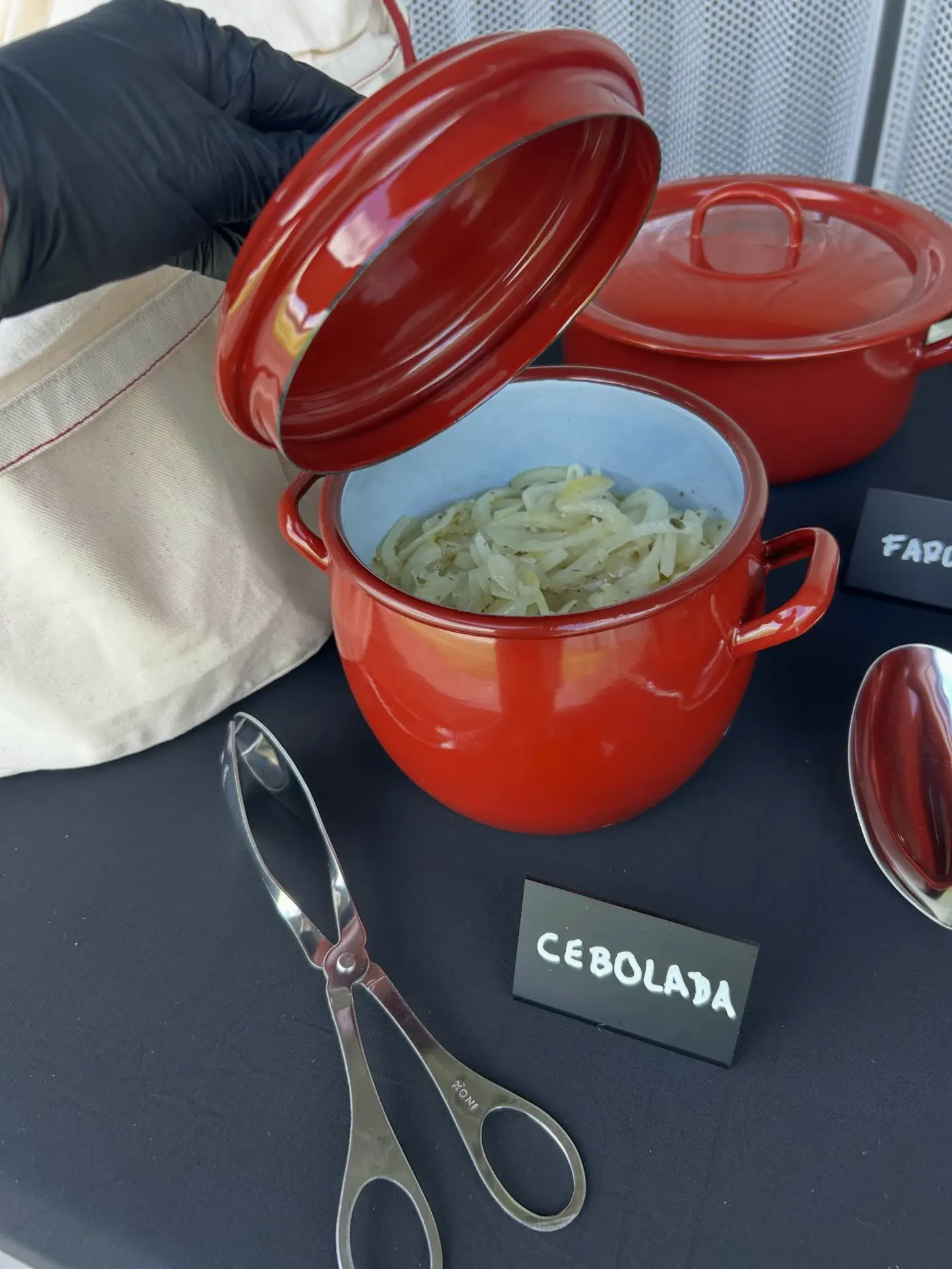 Panela vermelha com cebolada e pinça de servir