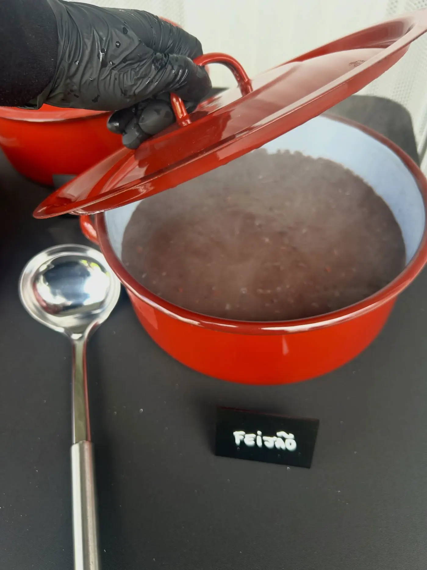Panela vermelha com feijão preto e concha