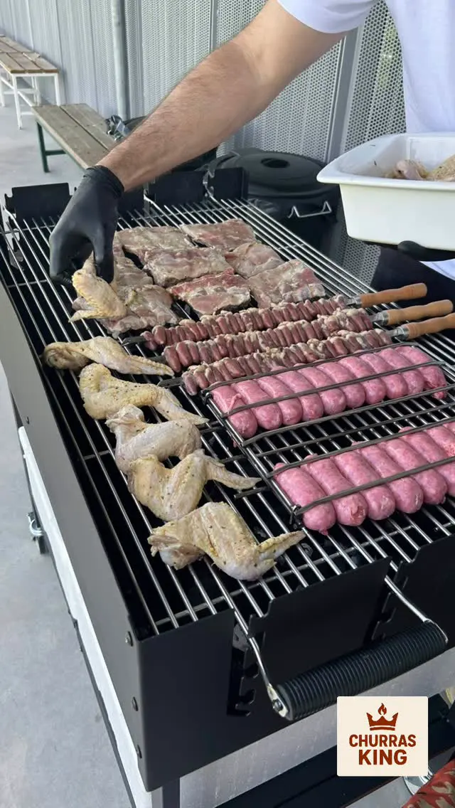 Grelha com asas de frango, linguiça e carnes a assar num evento do ChurrasKing