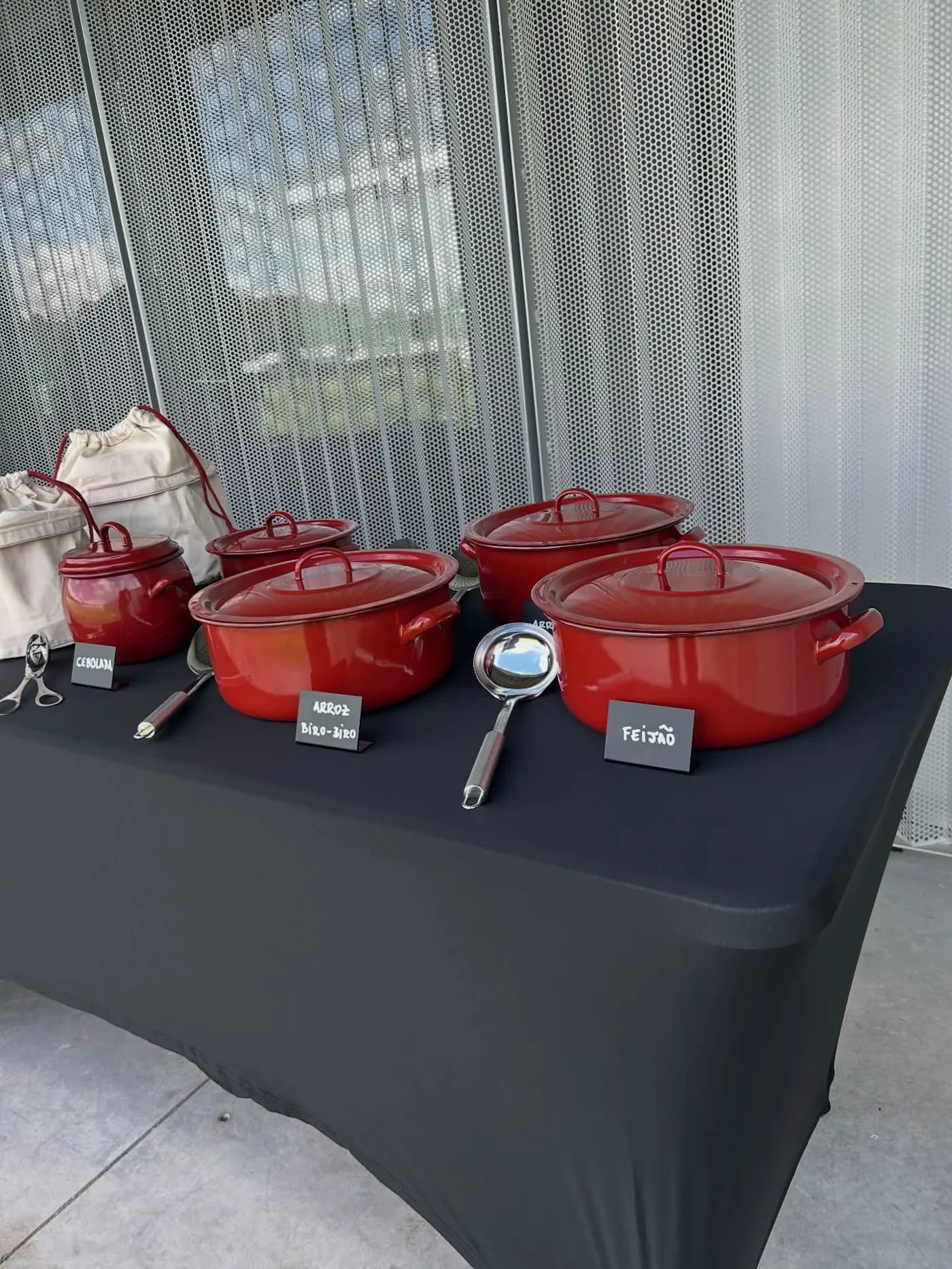 Mesa do buffet com as panelas vermelhas dos acompanhamentos